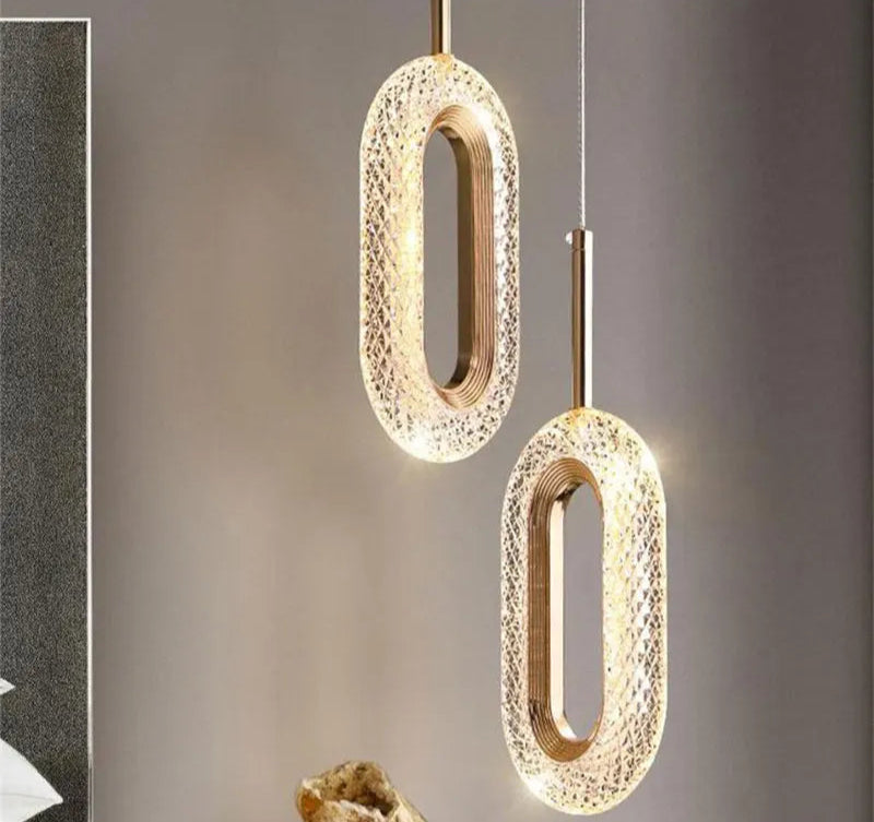 Pair of modern Nordic oval pendant lights with crystal texture and gold accents, ideal for bedroom or dining room lighting.