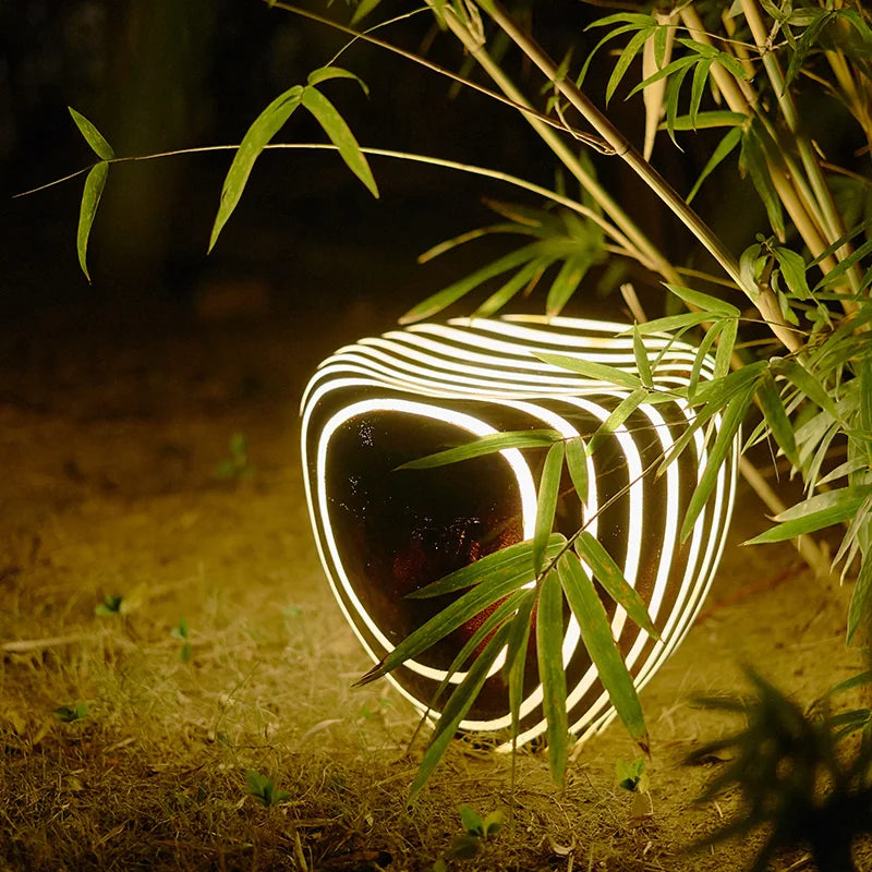 Outdoor light solar stone garden light placed near bamboo, emitting warm LED glow for stylish and eco-friendly landscape lighting.