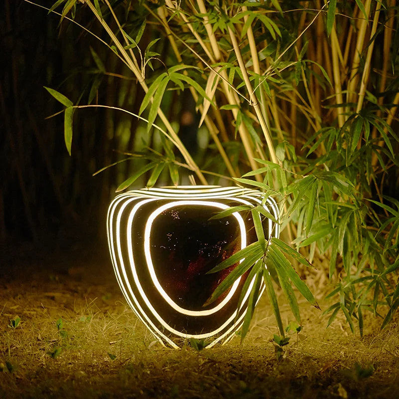 Creative solar-powered garden light with striped stone imitation design, lighting up garden foliage with soft ambient glow.