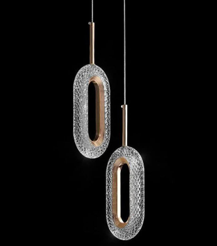 Two modern Nordic oval pendant lights with crystal and gold finish, suspended against a black background for dramatic effect.