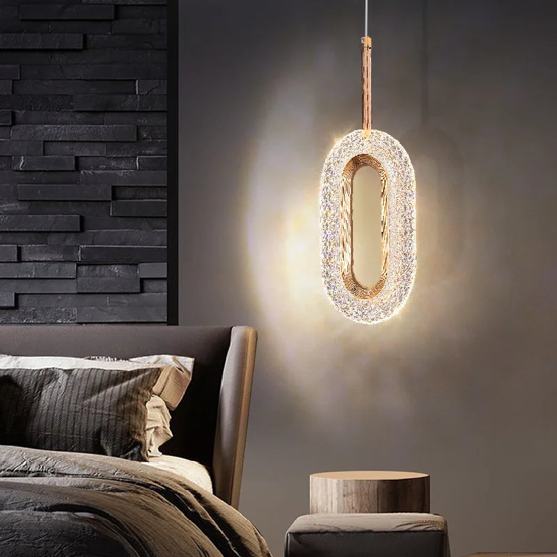 Single modern Nordic oval pendant light above nightstand, casting warm light in a cozy bedroom setting with dark accent wall.