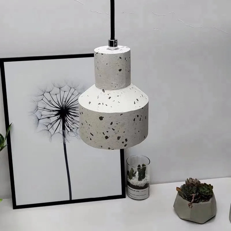 White terrazzo LED pendant lamp by LUXELY hanging above a framed dandelion print and succulents, ideal for bedside decor.
