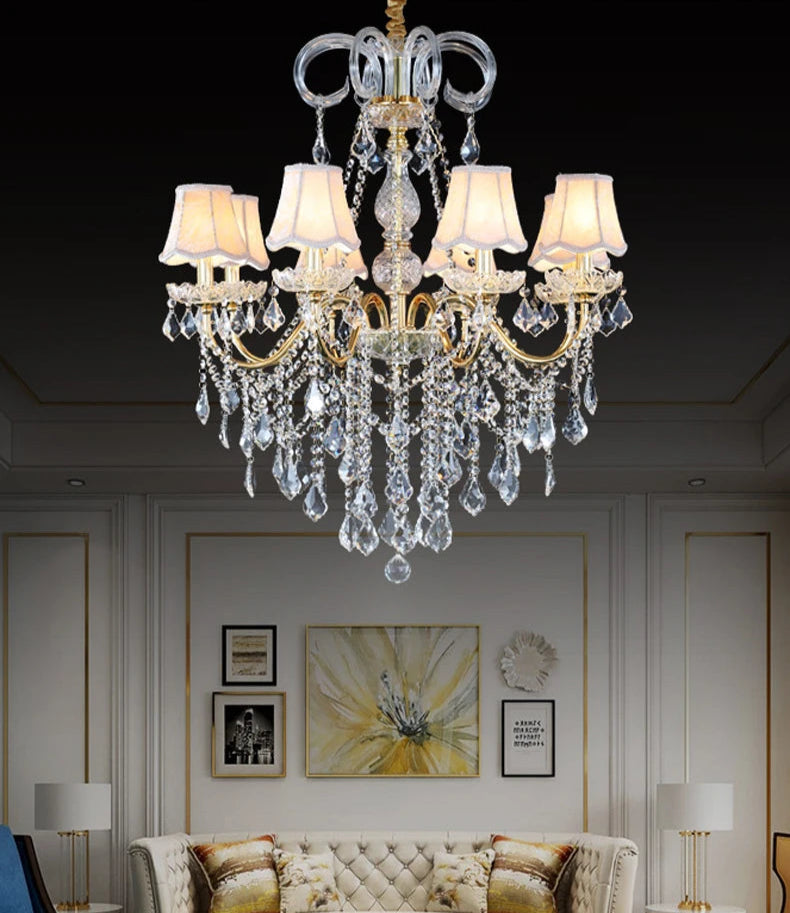 Golden crystal chandelier with fabric shades installed in a luxury living room, adding elegance and warm lighting.