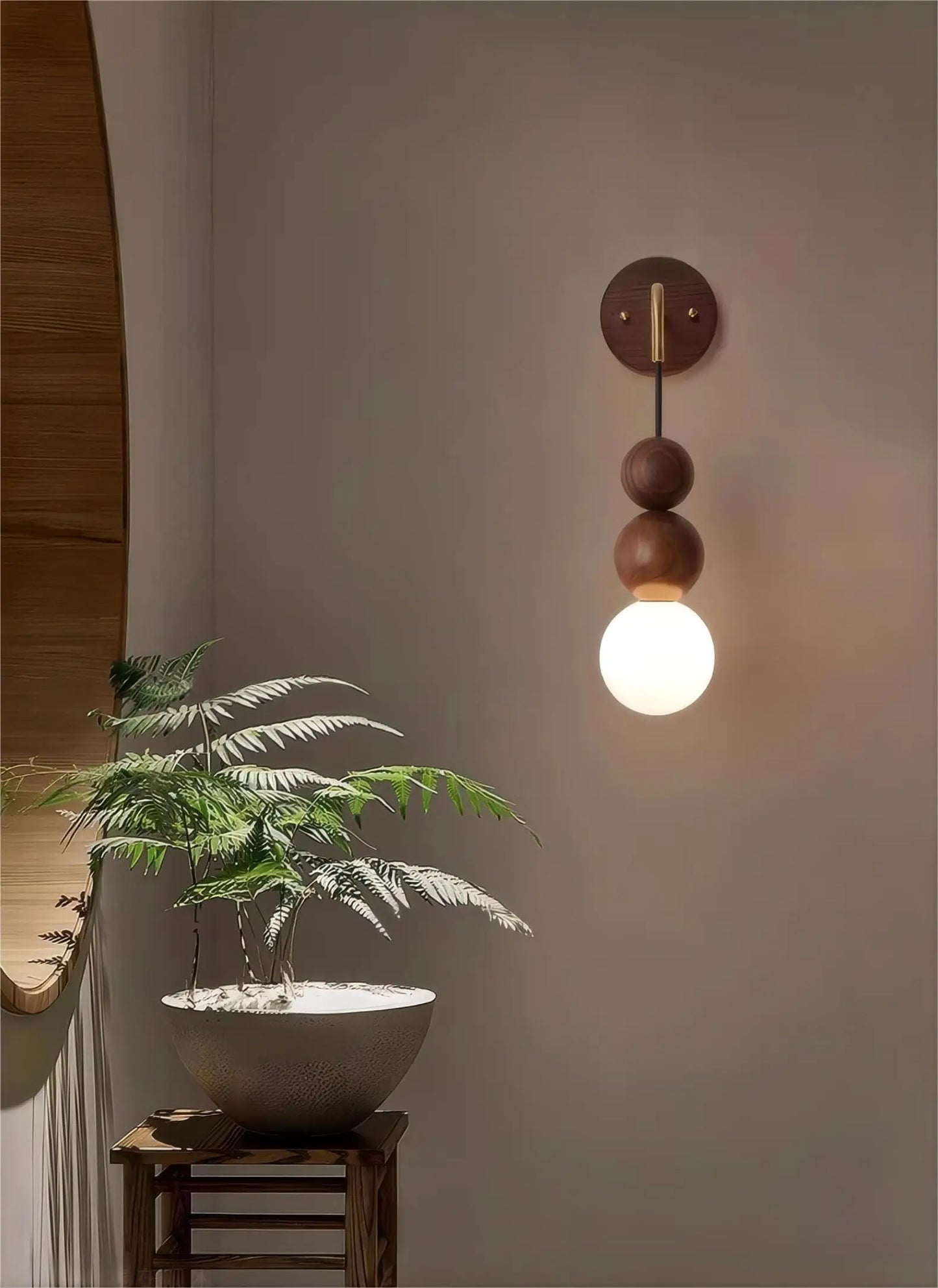 LUXELY walnut wood wall light with brass accent and glowing globe, mounted in a minimalist space with natural decor.