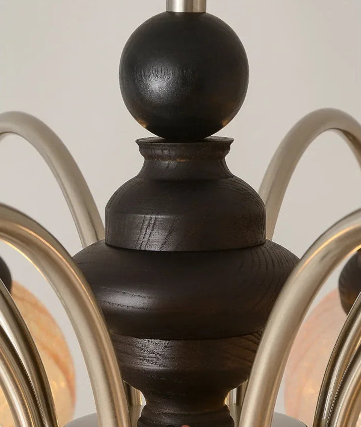 Close-up of the chandelier's black wooden central column and brushed gold arms, highlighting craftsmanship and modern design.