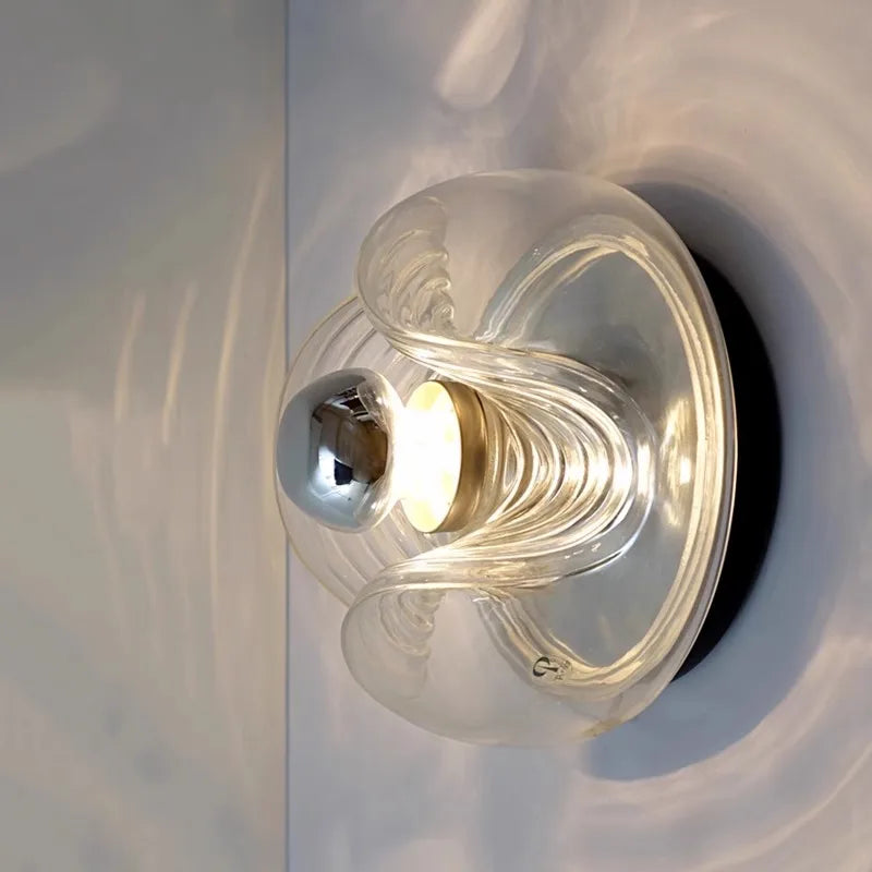 Side view of modern designer glass wall lamp with LED bulb, highlighting sculptural curves and ambient glow.