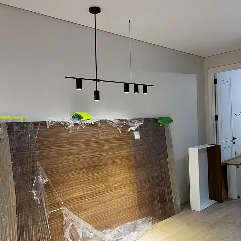 Modern minimalist spotlight bar ceiling light installed in a bedroom with wooden paneling, offering sleek and functional lighting.