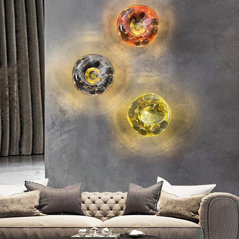 Set of three art deco lava wall lamps in silver, copper, and gold, mounted on a grey wall above a modern sofa.
