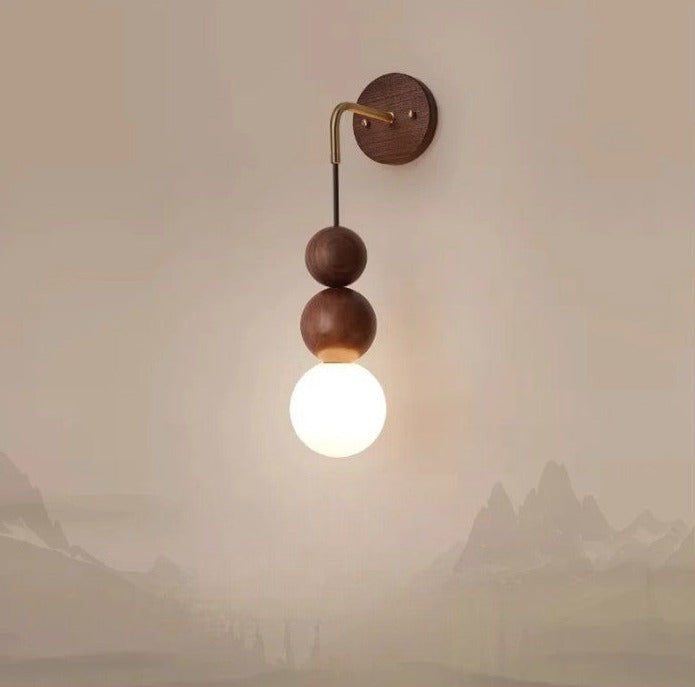 Modern walnut wood wall light by LUXELY featuring brass arm and glowing glass globe, ideal for bedroom or hallway decor.