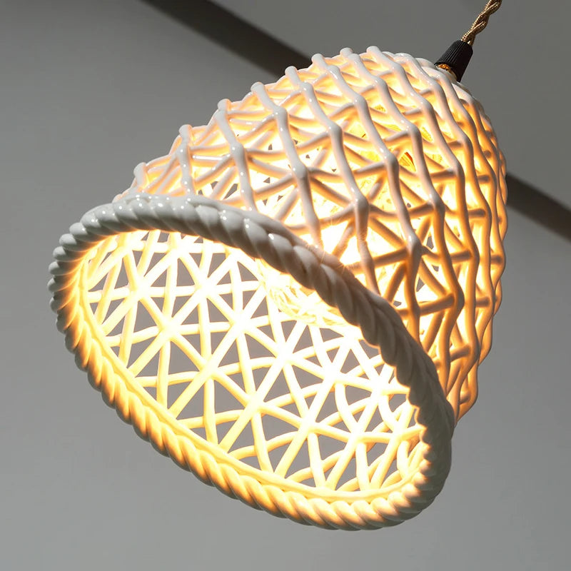 Close-up of LUXELY ceramic Japanese pendant light glowing warmly, showcasing its detailed white lattice pattern for cozy ambiance.