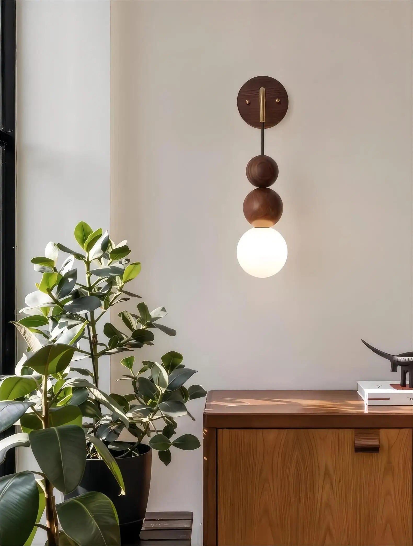 LUXELY walnut wood and brass wall sconce with glowing globe, styled above wooden cabinet in a modern interior.