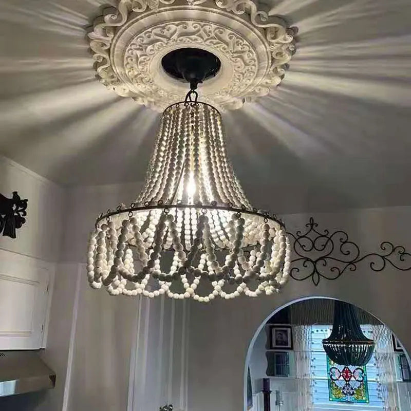Rustic Bohemian Wooden Bead Chandelier casting warm light patterns on ceiling, ideal for kitchen or dining room ambiance.