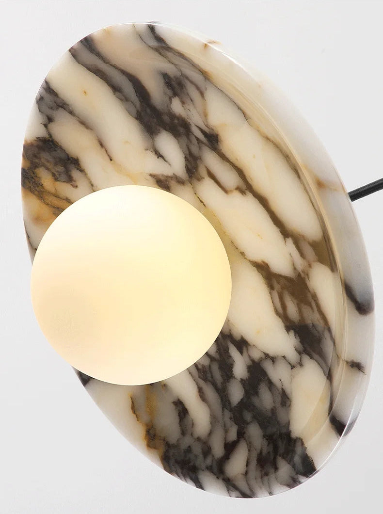 Underside view of the Marble Pendant Light with glowing LED bulb, emphasizing the rich black veining and smooth finish of the marble shade.