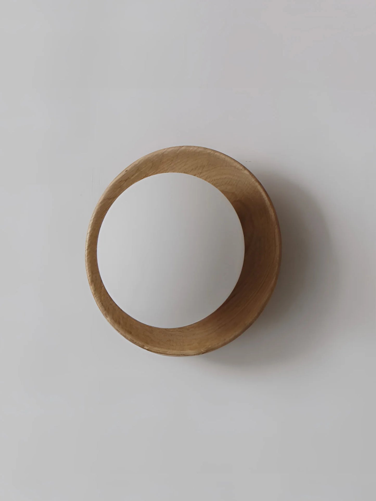 Scandinavian-style light wood wall sconce with soft white globe, perfect for cozy and elegant interiors.