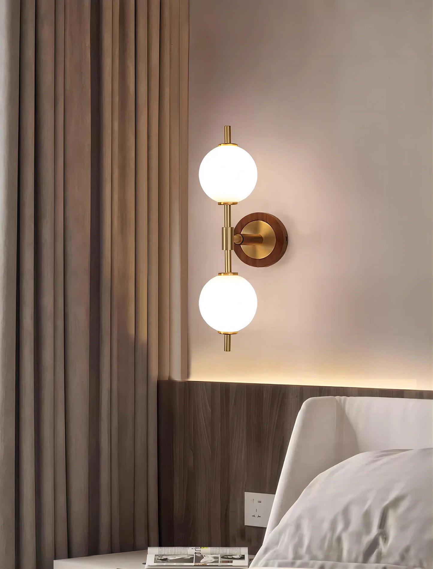 Brass accent wall lamp with modern design, mounted beside a bed with curtain backdrop for elegant bedroom lighting.
