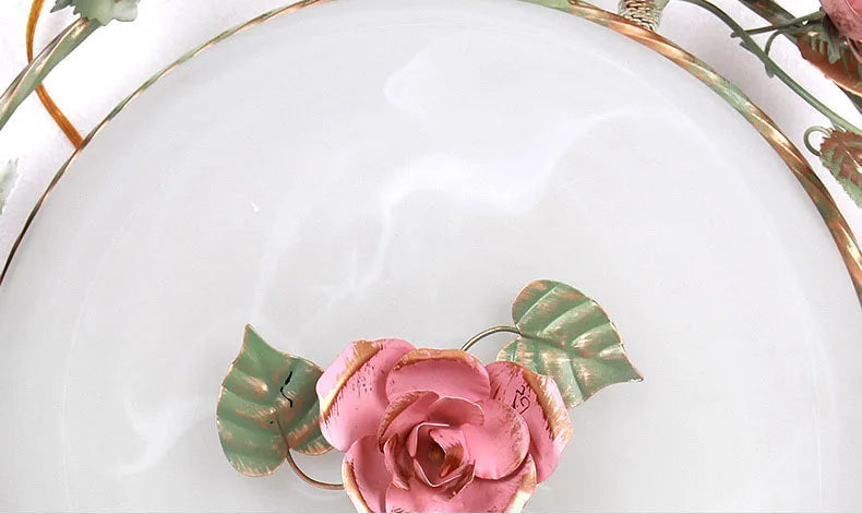 Center detail of romantic pink chandelier with rose and green leaves. French rose design adds charm to lighting fixture.