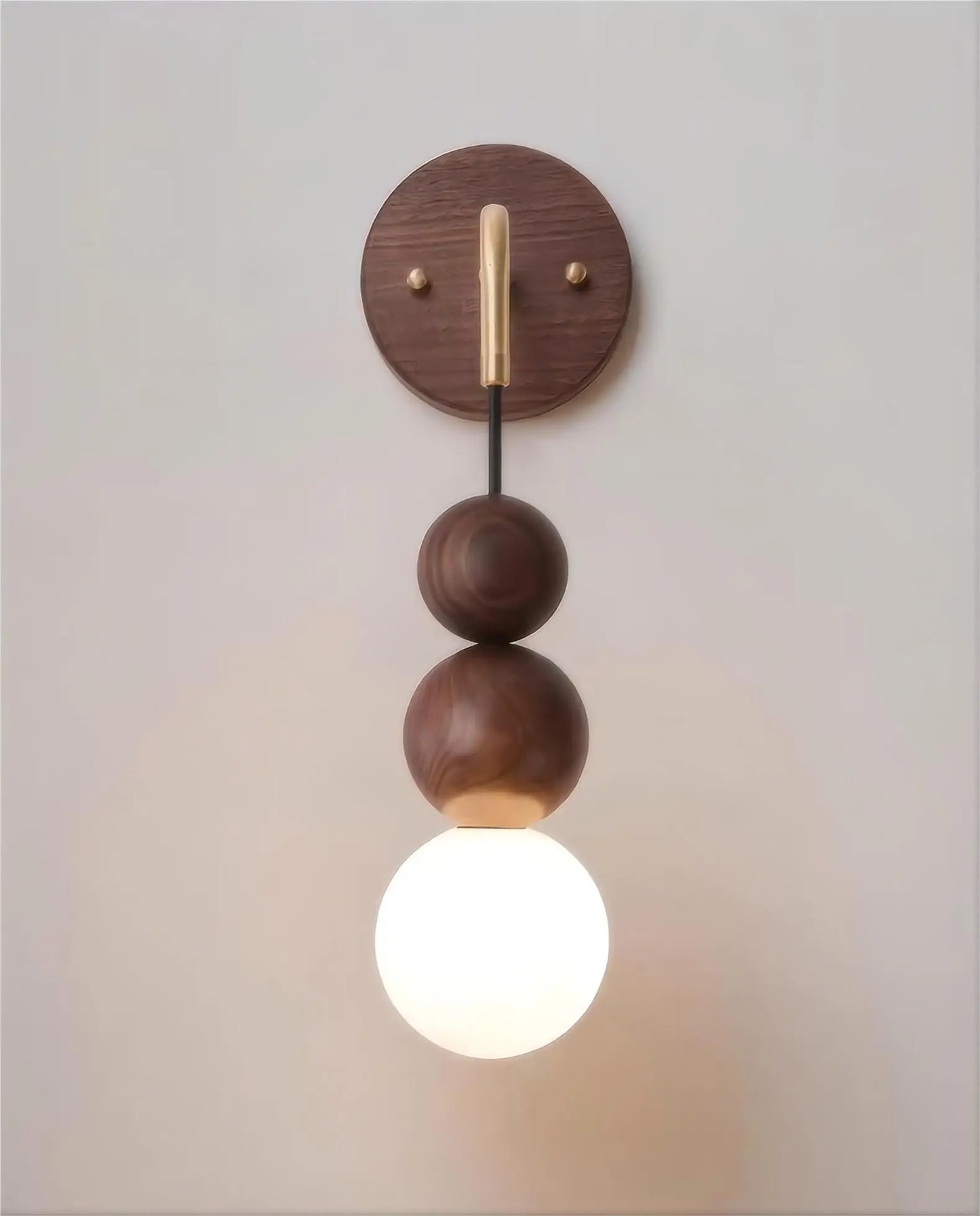 Front view of LUXELY walnut wood wall sconce with brass detail and glowing glass globe, perfect for ambient lighting.