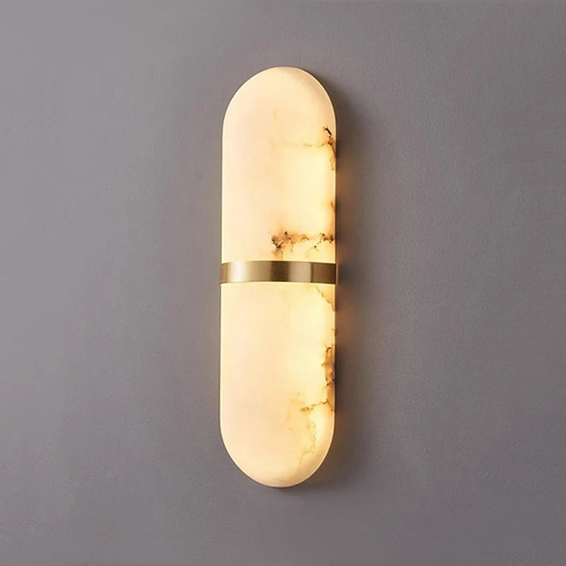Oval marble stone wall lamp illuminated with warm light and gold brass accent, ideal for luxury interior wall lighting.