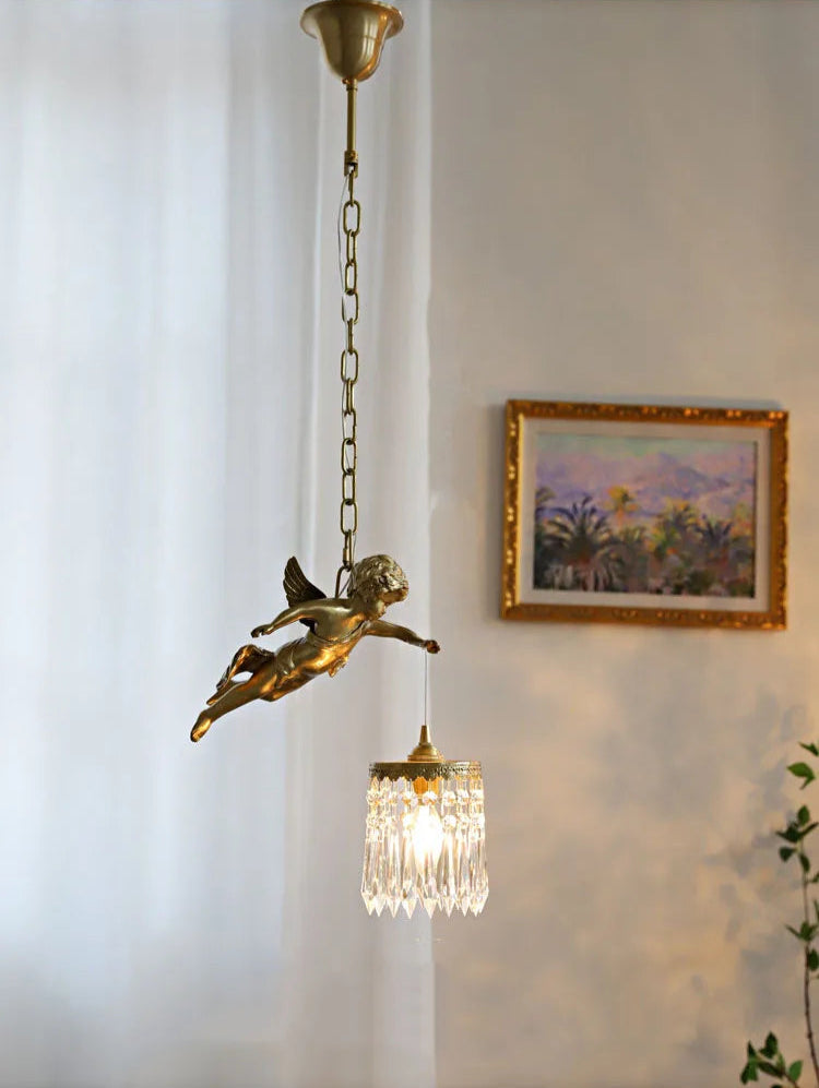 Copper angel chandelier light with crystal pendant softly illuminating a classic room with framed artwork.