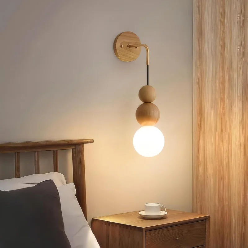 Light oak version of LUXELY wall light with brass accent and glowing glass globe, perfect for minimalist bedroom settings.