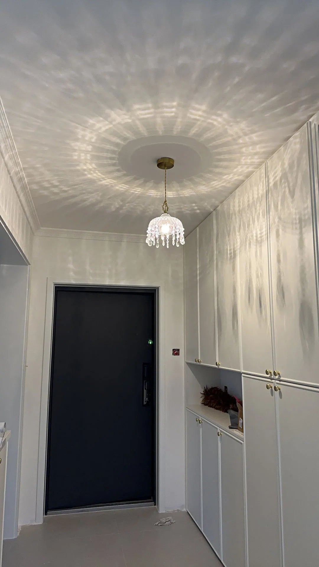 French Vintage Crystal Chandelier - Copper Hanging Lamp in entryway, casting elegant reflections on white cabinetry.