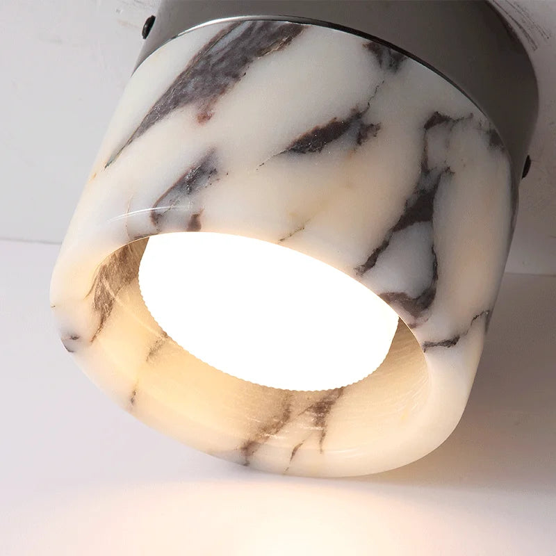 Illuminated Nordic LED wall sconce with warm light glowing through marble-effect glass, ideal for ambient hallway lighting.