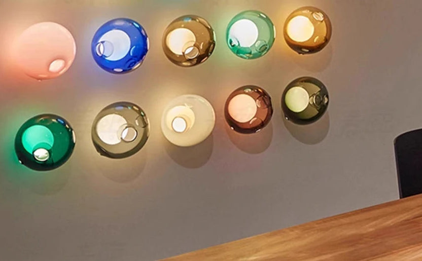 Wide variety of colorful glass ball LED wall lights displayed on a wall, perfect for modern bedroom or café lighting décor.