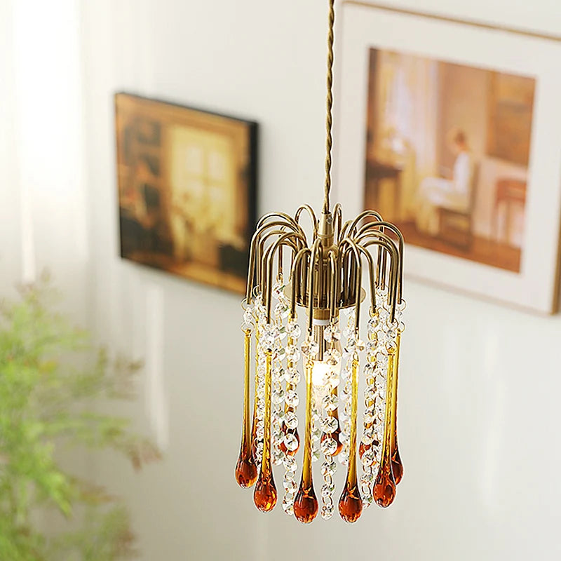 Hanging vintage water drop glass chandelier with copper finish, styled in a softly lit room with classic wall art.