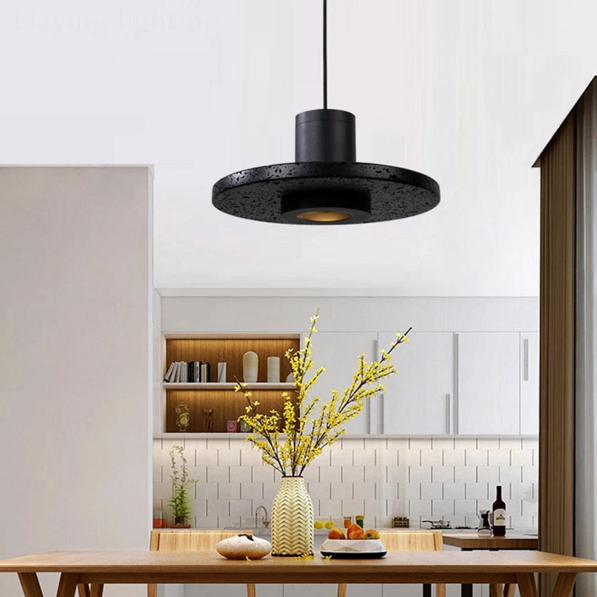 Single LUXELY travertine pendant light above a kitchen island, blending industrial style with energy-efficient LED lighting.