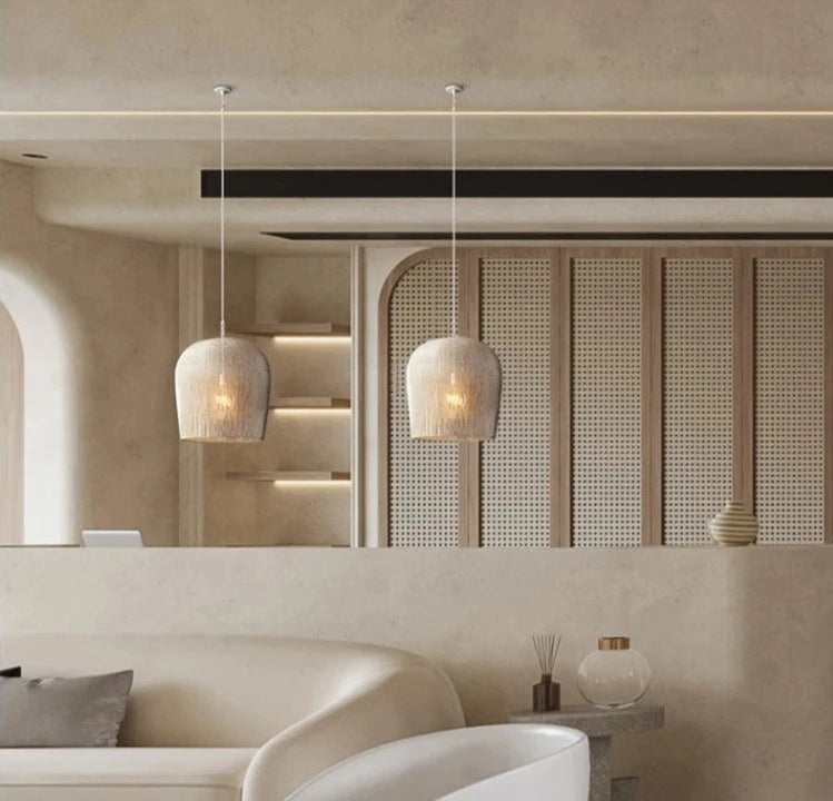 Pair of white LUXELY rattan pendant lights above a curved sofa, enhancing a modern lounge with soft, natural lighting.