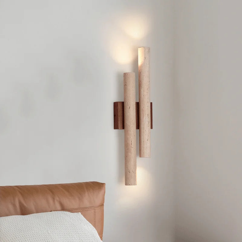 Wall-mounted travertine stone bedroom wall lamp with warm LED strip lighting, shown beside a leather headboard for cozy room ambiance.