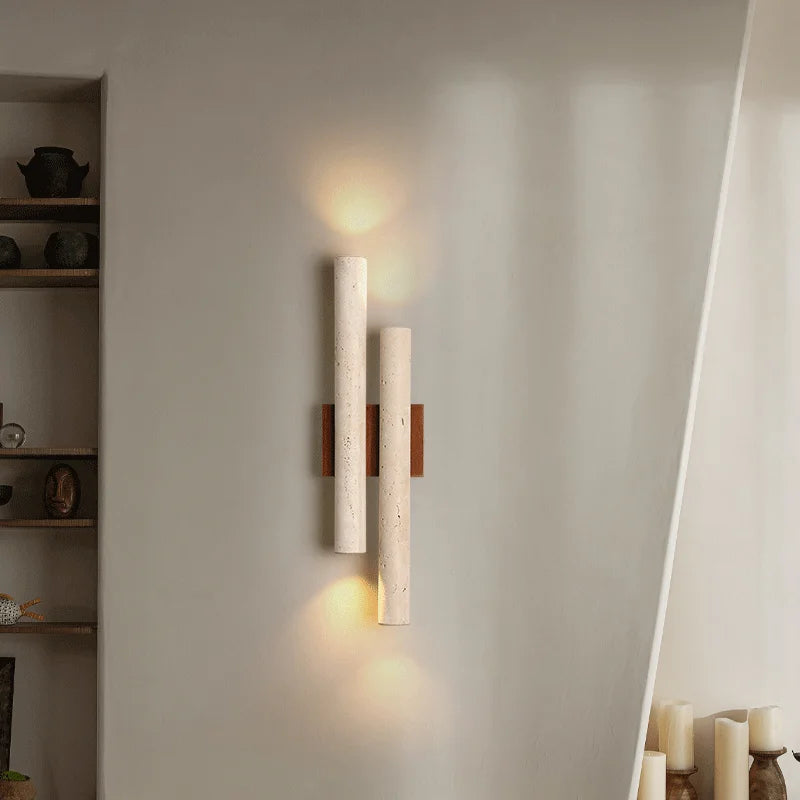 Travertine stone wall lamp with wood accent illuminating a living space, offering vertical ambient lighting for modern interior decor.