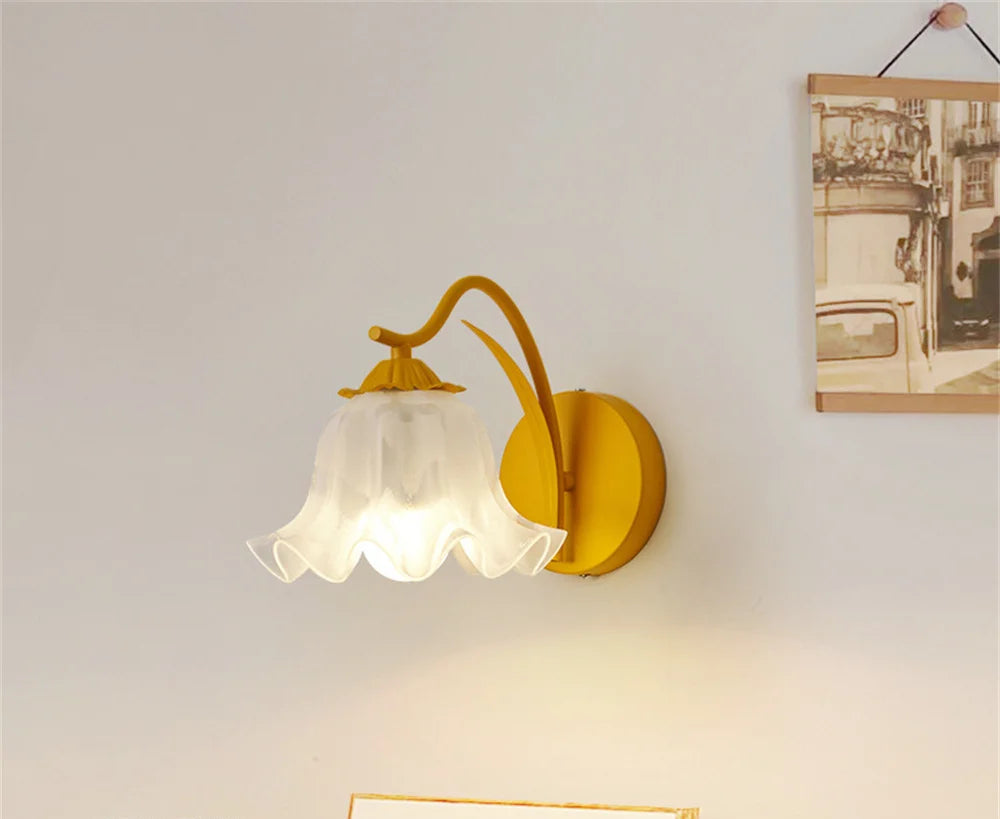 Yellow French flower sconce with elegant glass petal design, wall-mounted in a modern home setting for ambient bedroom lighting.