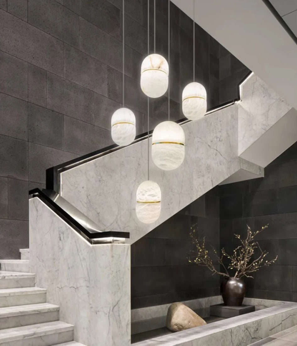 Cluster of oval marble LED pendant lights in a luxury stairwell. Marble LED pendant light – modern ceiling lamp dimmable for upscale interiors.