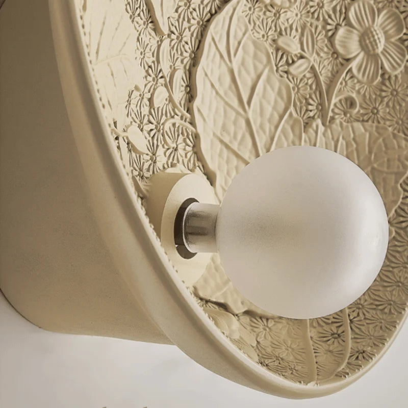 Detail view of art deco wall lamp bulb and floral relief, vintage round sconce for elegant bedroom or restaurant walls.