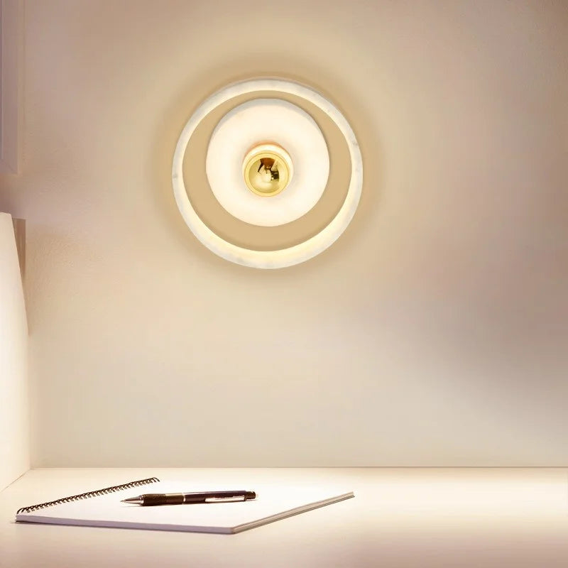Marble round wall lamp with glowing LED light, mounted above a desk, ideal for bedroom or office ambient lighting.