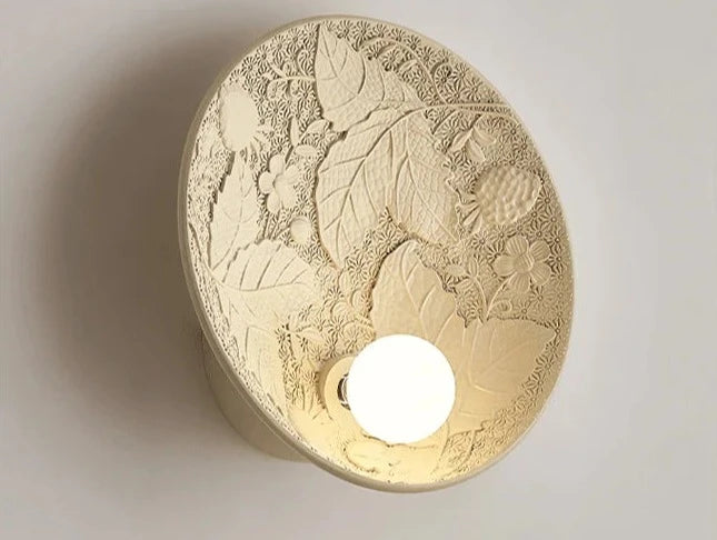Angled view of vintage French round wall lamp with floral relief, ideal for classic living room or hallway lighting.
