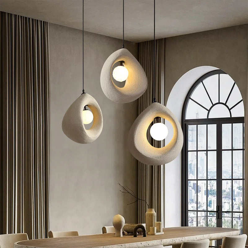 Nordic wabi-sabi LED pendant lights in art deco style hanging above a dining table, enhancing the space with minimalist elegance and soft lighting.