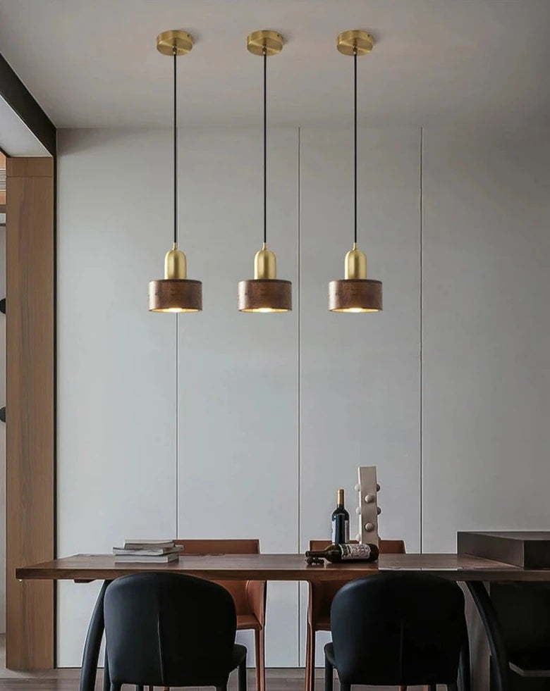 Three LUXELY Nordic walnut wood pendant lights over a dining table, enhancing modern dining room aesthetics with warm lighting.