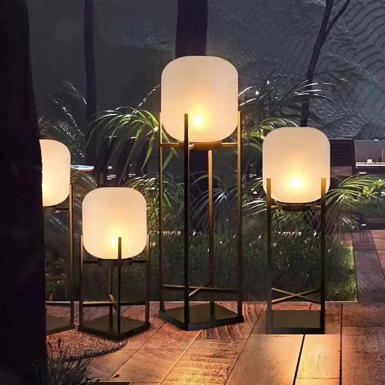 Multiple LUXELY IP65 solar garden lights in varying heights lighting a landscaped garden path at night.