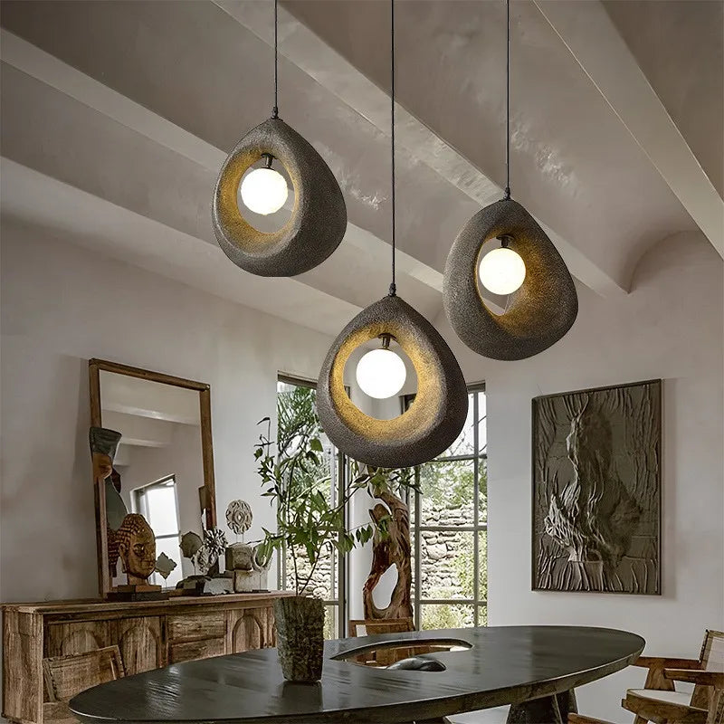 Art deco pendant lights in wabi-sabi style suspended over a rustic dining table, blending Japanese minimalism with modern LED lighting.