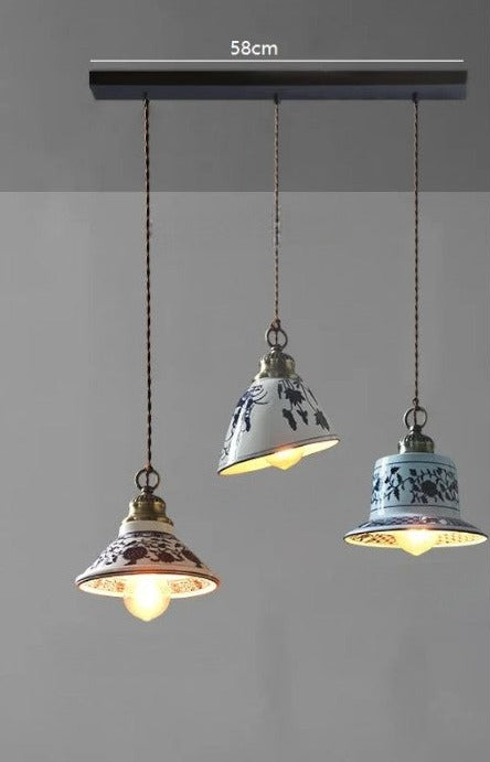 Three assorted ceramic pendant lights with floral designs on a 58cm bar, ideal for farmhouse kitchen or dining lighting.