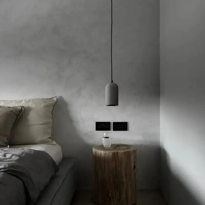 Single gray LUXELY cement pendant lamp hanging beside a bed. Ideal for bedroom ambient lighting with a minimalist touch.
