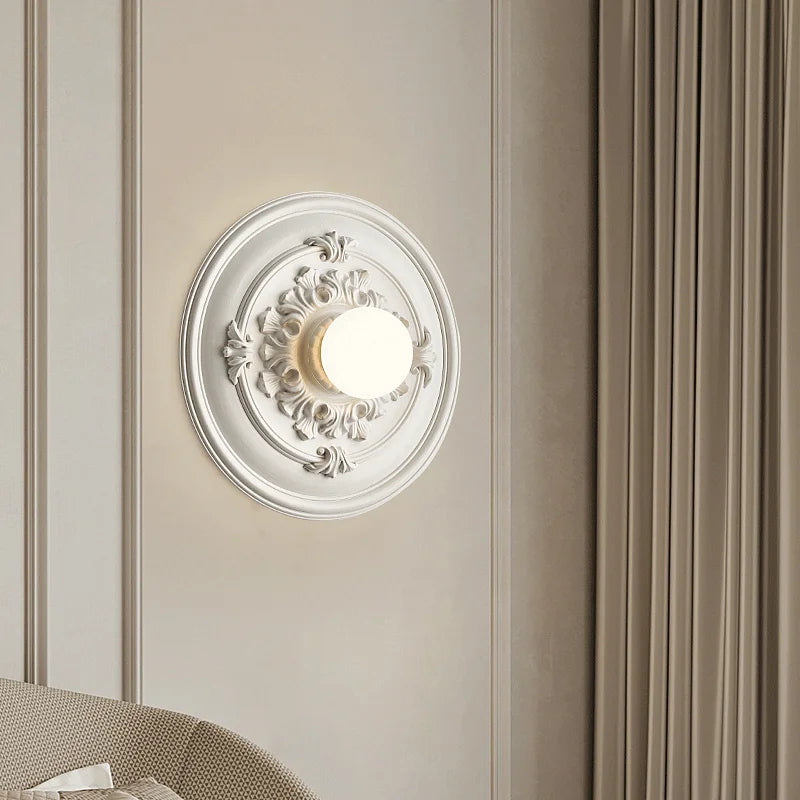 White LUXELY retro wall sconce with intricate detailing, installed in a modern bedroom for a luxurious lighting touch.