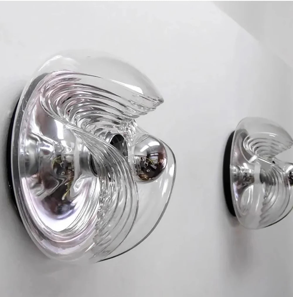 Side-mounted designer glass wall lamps with LED bulbs, showcasing elegant curves and reflective surfaces.