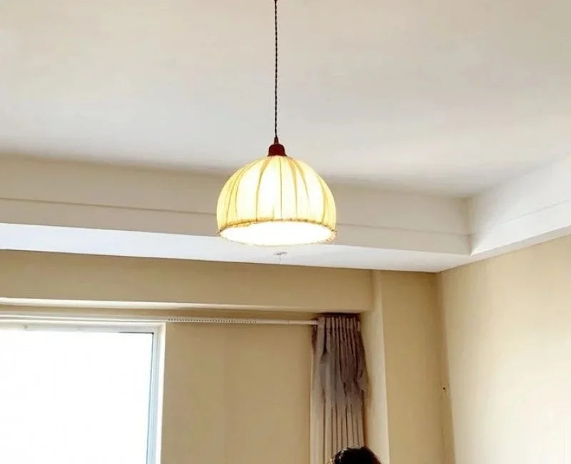 Nordic Japanese fabric pendant lamp installed in ceiling, casting warm light in a minimalist bedroom setting.