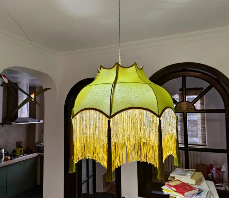 Green velvet chandelier with golden tassels in a rustic kitchen, adding a retro touch to the interior lighting.