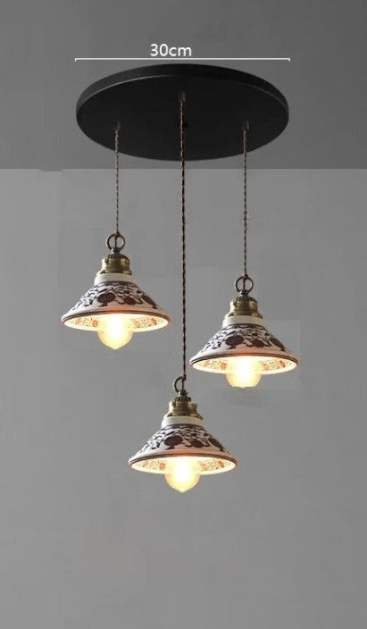 Triple cone-shaped ceramic pendant lights with red floral design on a 30cm base, perfect for rustic dining areas.