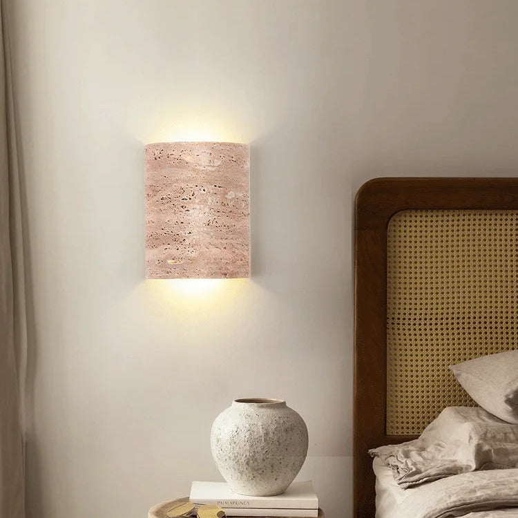 Travertine wall lamp IP65 beside bed in cozy bedroom, combining wabi-sabi style with functional wall lighting.