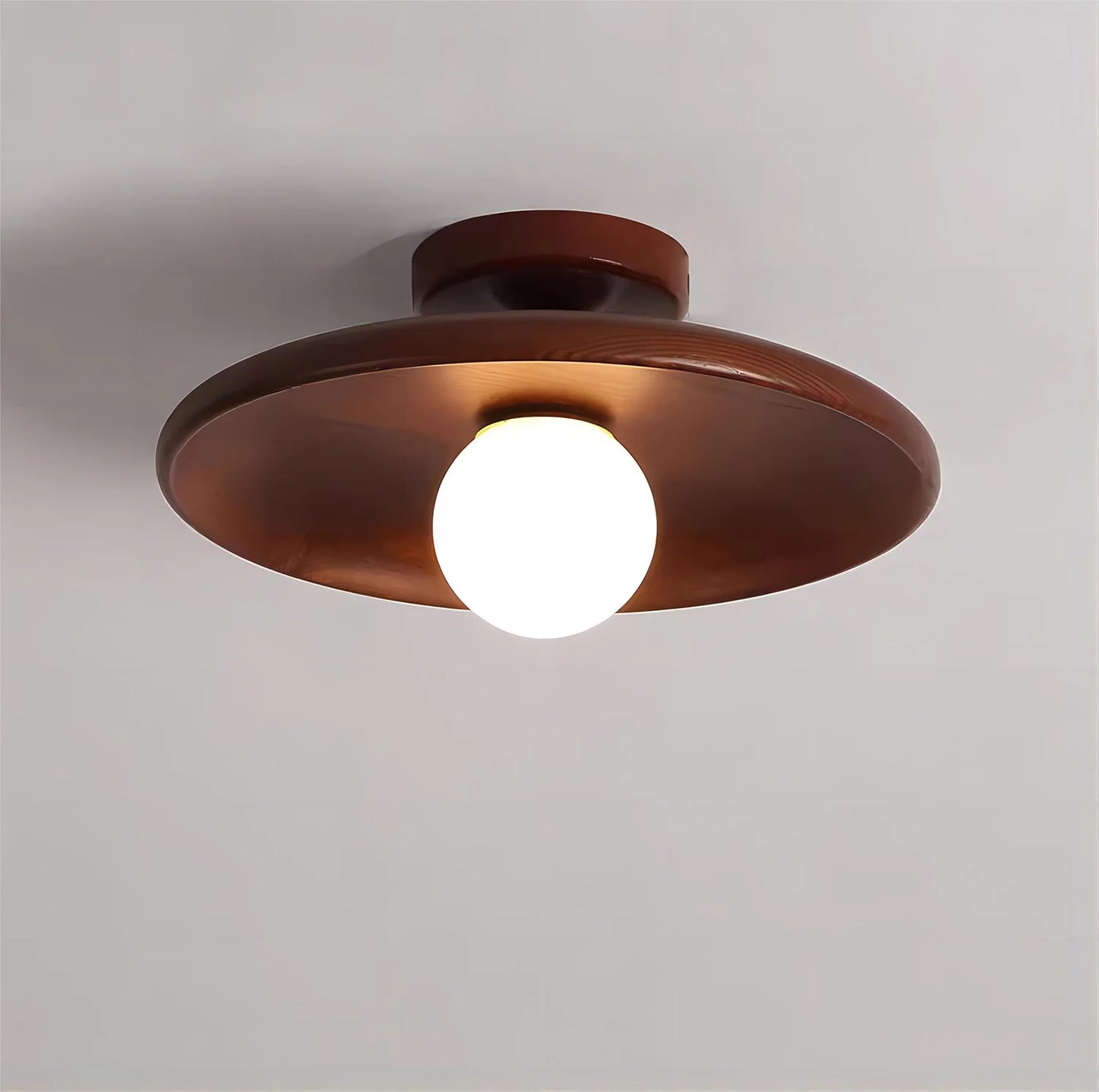 Smooth walnut wood ceiling light with a round flush mount design and central globe bulb, perfect for warm ambient lighting.